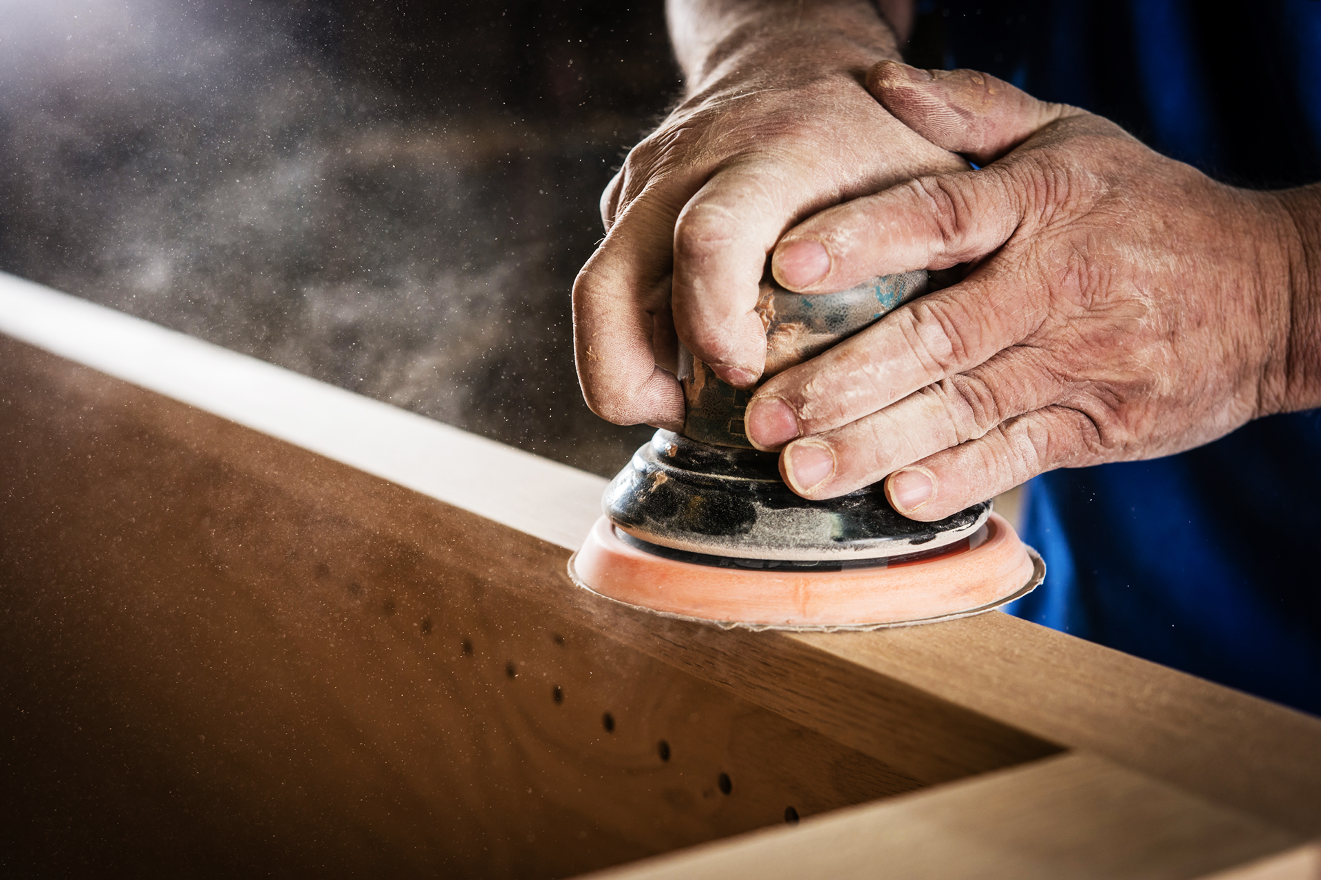 Commercial woodworking photograph showing hands sanding furniture